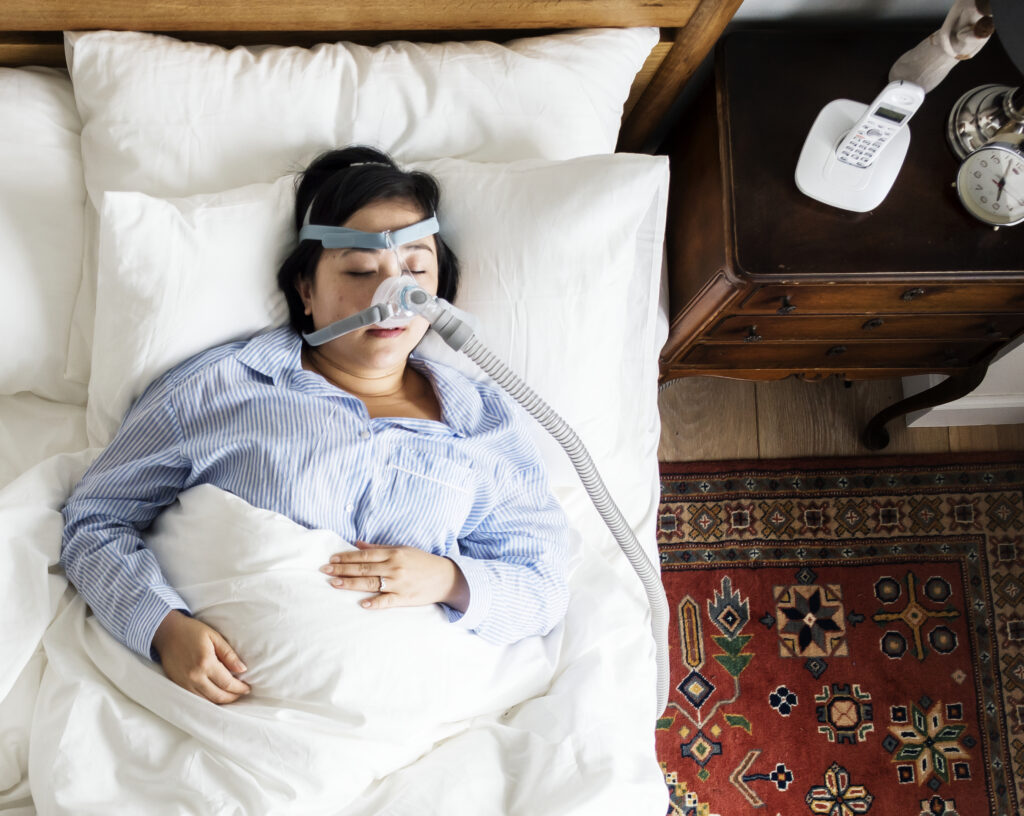 A woman sleeping with a sleep apnea mask or CPAP Machine
