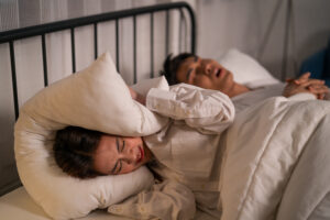 Asian woman who is frustrated from her husband snoring due to sleep apnea and wondering is sleep apnea genetic?